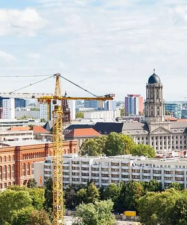 Vogelperspektive auf das Rote Rathaus in Berlin mit historischen und modernen Gebäuden drumherum sowie einem Kran.