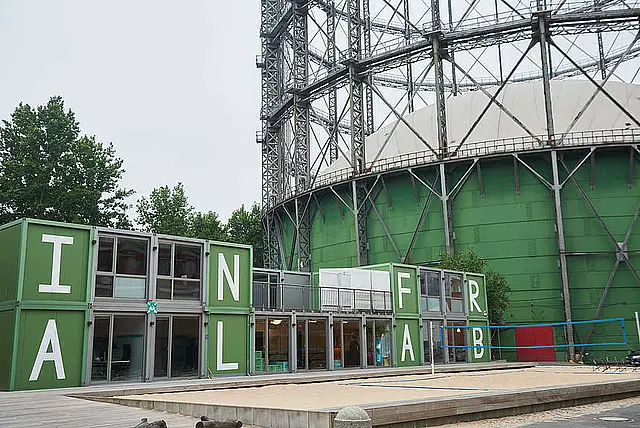 Moderne Containerarchitektur mit farbenfrohen Buchstaben "InfraLab" und Volleyballplatz.