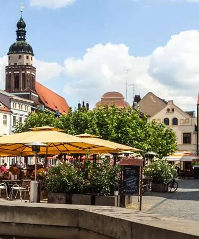 Blick auf einen malerischen Marktplatz mit Brunnen, Cafés und historischen Gebäuden