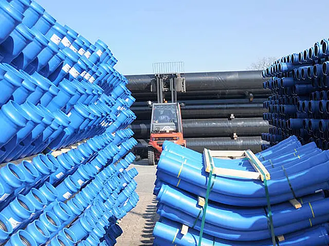 Lager von Wasserrohren in blau mit einem Gabelstapler im Hintergrund