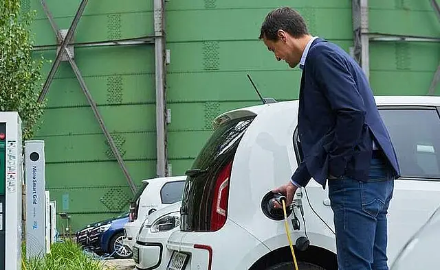 Mann lädt Elektroauto an Ladestation